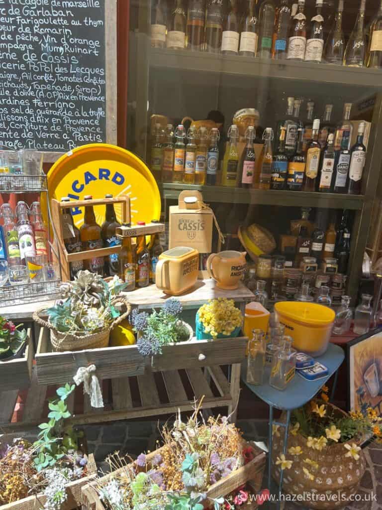 Display of Provençal goods in a Cassis shop window, including lavender sachets, honey, local wines, and artisanal kitchenware.
