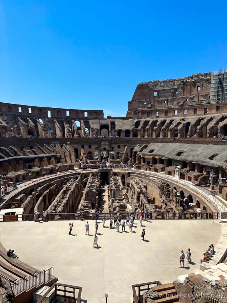 Middle of the arena in the Colosseum in Rome against a blue sky.