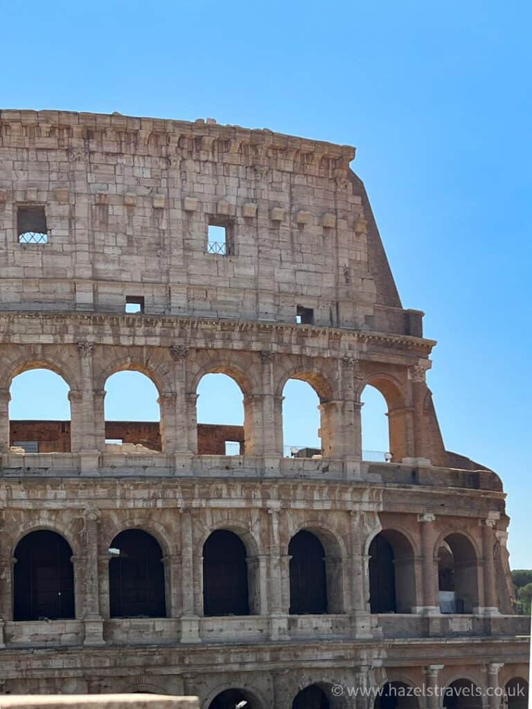 Visiting Rome: Close of up the Colosseum in Rome against a blue sky.