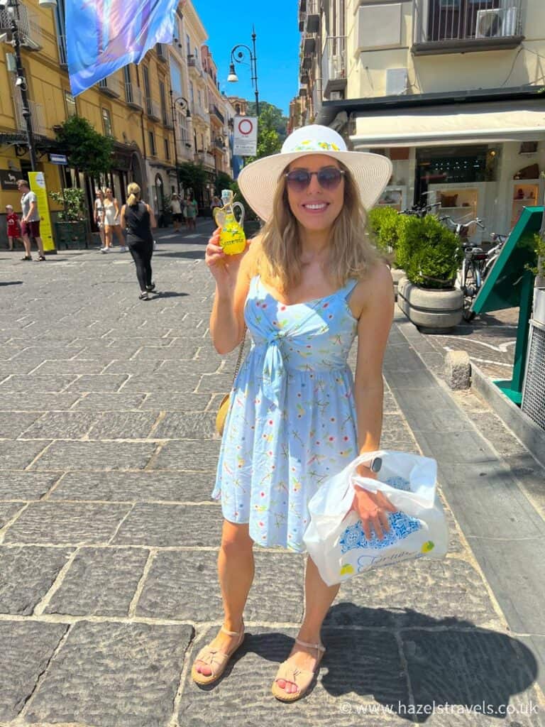Woman in blue dress holds up a bottle of limoncello in Sorrento, Italy.