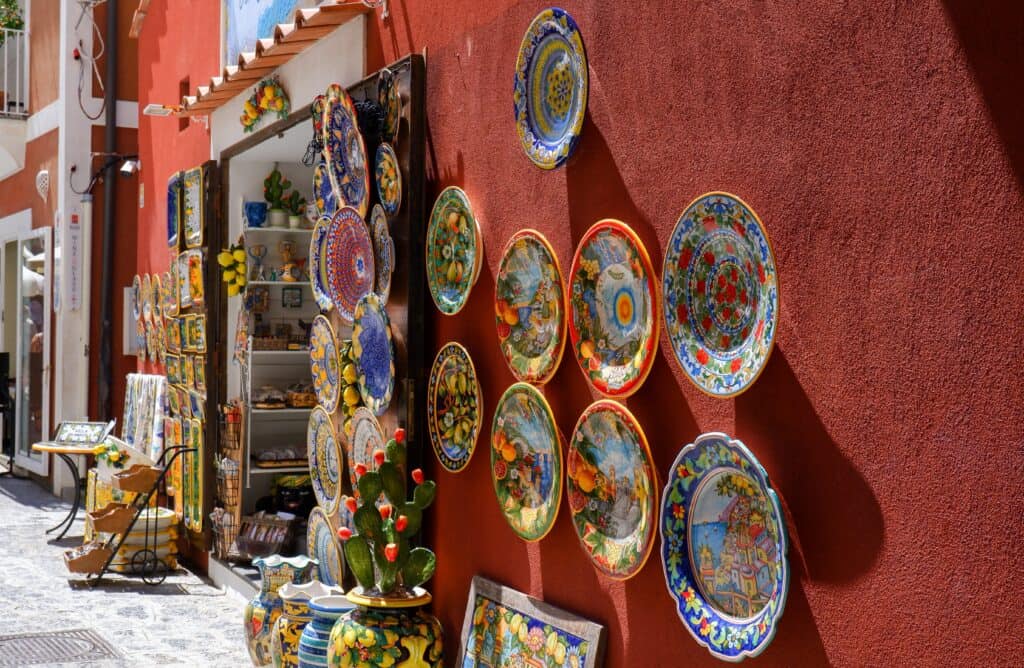 Positano Ceramics' vibrant ceramic plates adorn a red wall outside the shop, hinting at the treasures that await inside.