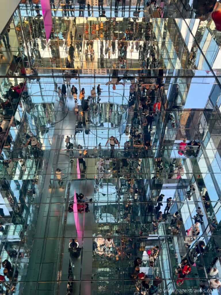 Mirrored walls and floors at Summit One Vanderbilt observation deck in NYC. Lots of people are reflected in all of the surfaces, creating an optical illusion of sorts. 