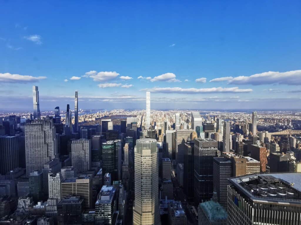 The view from Summit One Vanderbilt skyscraper, looking across New York City to central Park, with a blue sky and white clouds. 