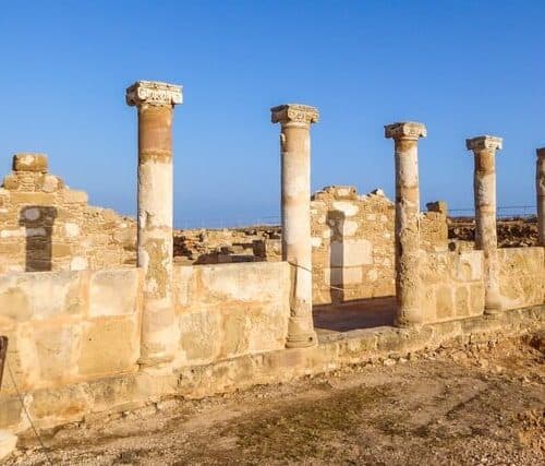 Ruins of an ancient temple, what is left are temple columns, Kato Paphos Archeological Park. Sandy color of the construction. Clear and blue sky.
