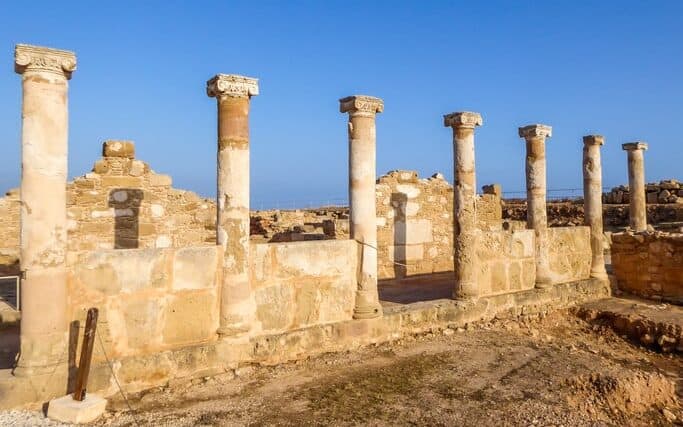 Ruins of an ancient temple, what is left are temple columns, Kato Paphos Archeological Park. Sandy color of the construction. Clear and blue sky.