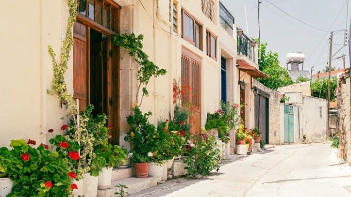 Sunny narrow street in old village Omodos on Cyprus. Stone walls and vibrant green plants on a sunny day