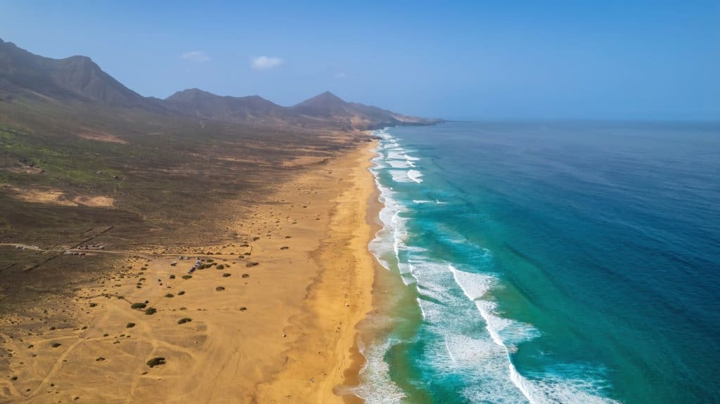Volcanic beach with high dunes to the left and turqouise sea to the right