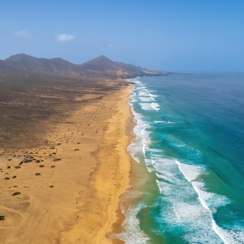 Volcanic beach with high dunes to the left and turqouise sea to the right