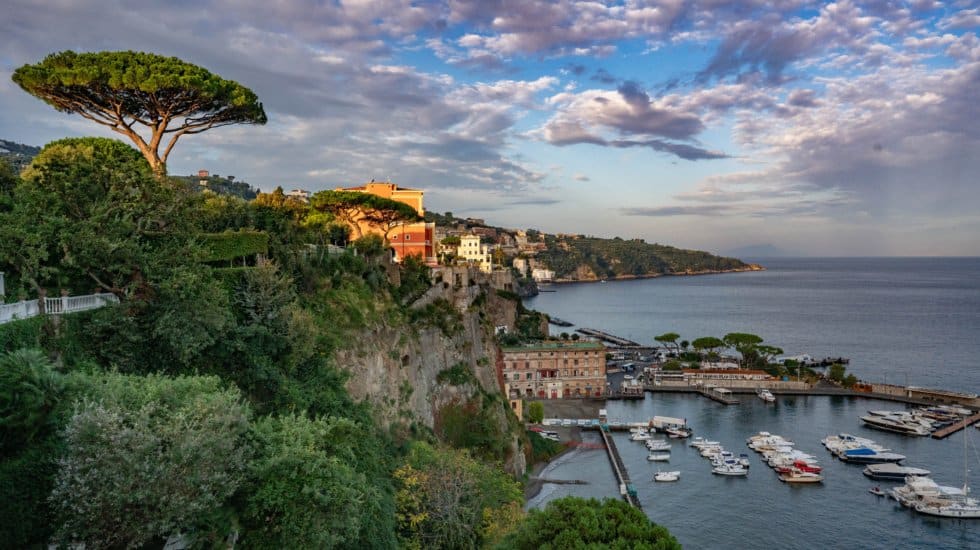 Landscape view of Sorrento harbour with green cliffs and trees on the left and boats on the right