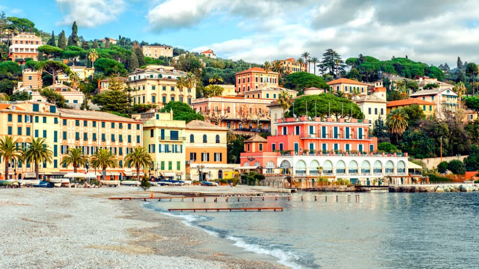 a group of colourful buildings sitting on top of a hill next to a body of water