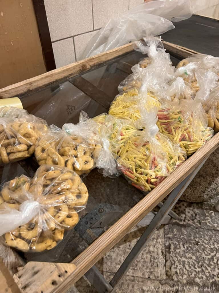 Plastic bags filled with various pasta and snacks displayed on a wooden table.