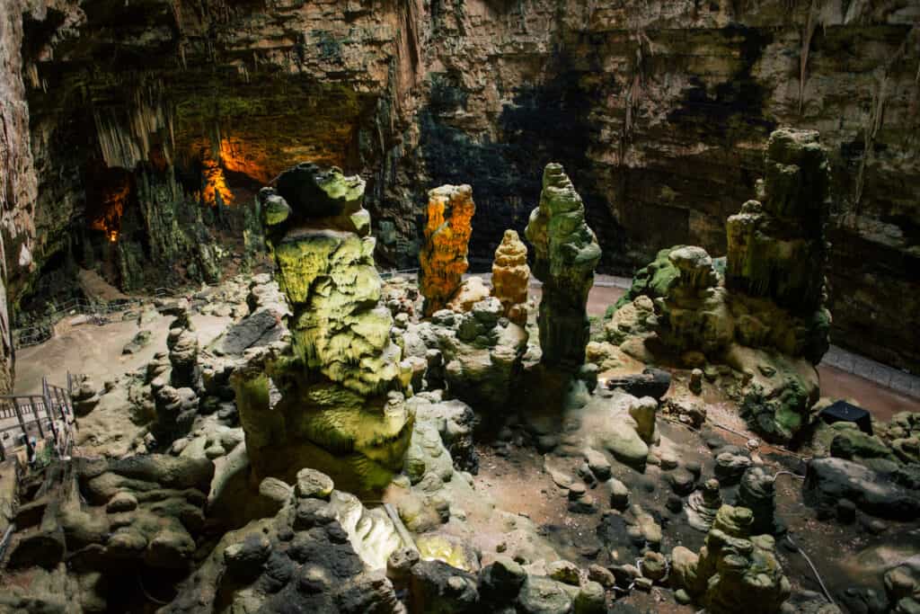 A cavernous underground space with large, irregularly shaped rock formations and various light sources illuminating the scene.