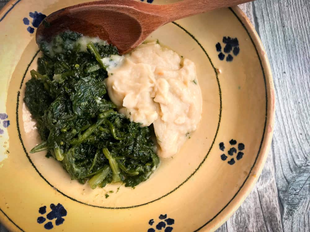 a wooden spoon is in a bowl of food.