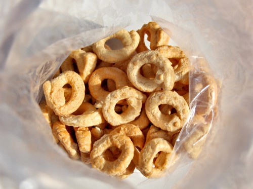 a plastic bag filled with donuts sitting on top of a table.