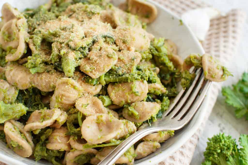 a white bowl filled with pasta and broccoli.