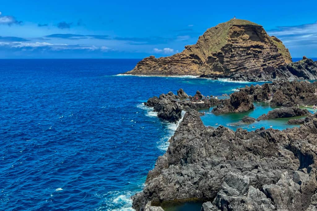 A rocky cliff overlooking the ocean and a blue sky at Porto Moniz Madeira.