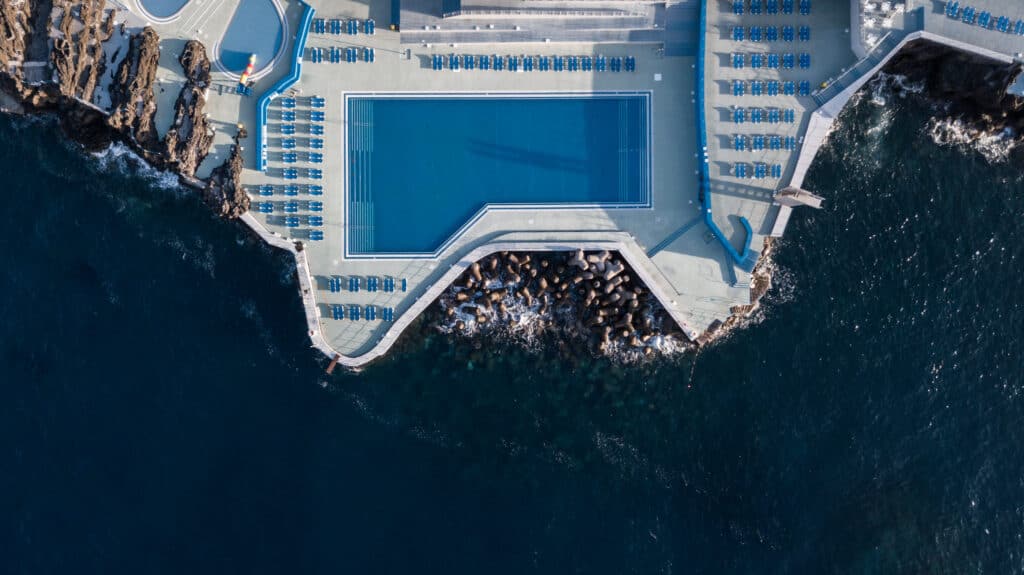 An aerial view of a swimming pool on the edge of the ocean in Funchal Madeira.