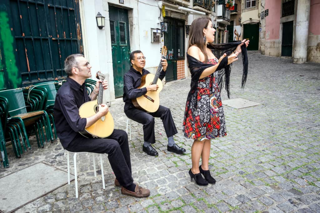 A group of people playing guitars on a cobblestone street in Funchal Madeira.