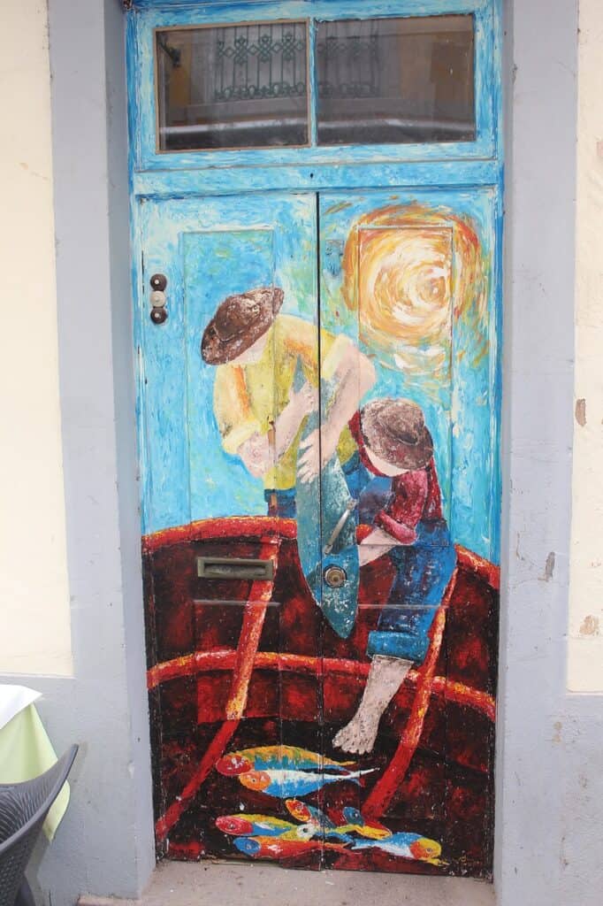 A blue door with a painting on it in Madeira in Santa Maria Street Funchal
