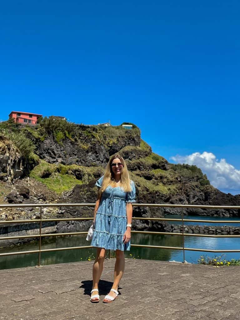 Woman in a blue dress standing in front of a cliff at Seixal in Madeira.