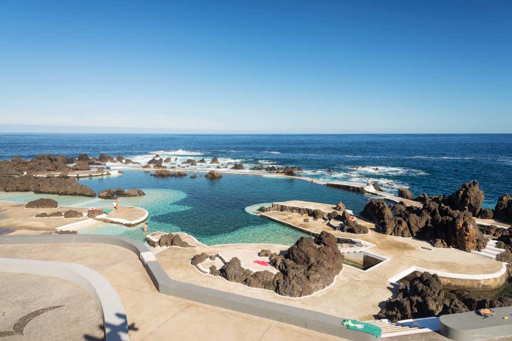 Natural ocean pools with people enjoying the water on a sunny day at Porto Moniz Madeira