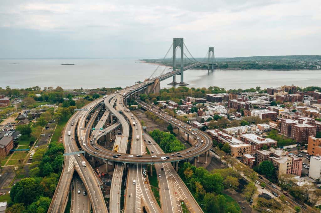 Aerial view of a suspension bridge with intertwining roadways leading into a densely populated area near a body of water. one of the most famous bridges in New York City. 