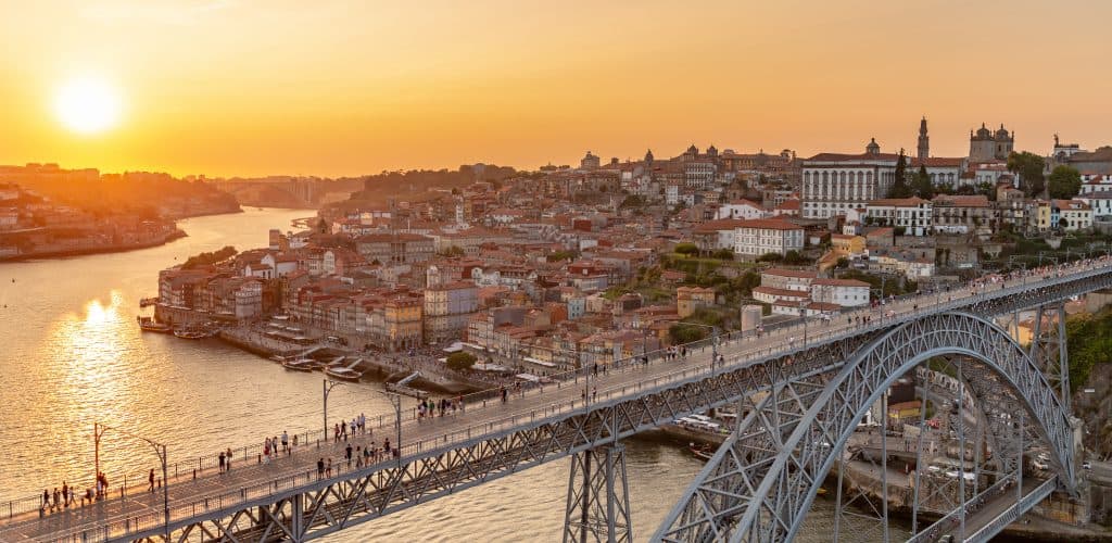 Sunset view over the douro river, featuring the dom luís i bridge and the porto cityscape in portugal.