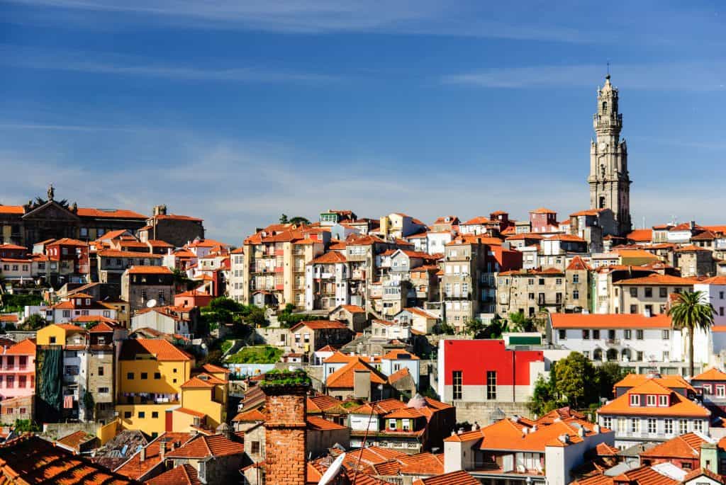 View of porto, showing densely packed colorful houses and the prominent clerigos tower under a clear blue sky.