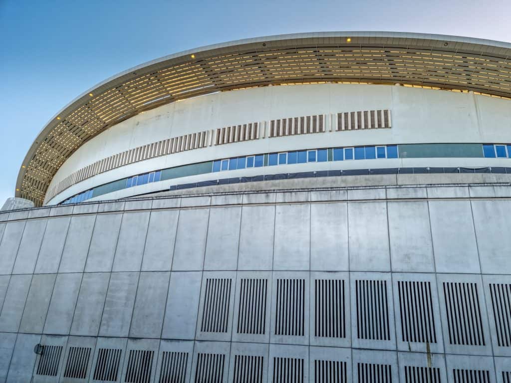 Side view of the modern circular stadium of FC Porto with horizontal slat design and a clear blue sky background.