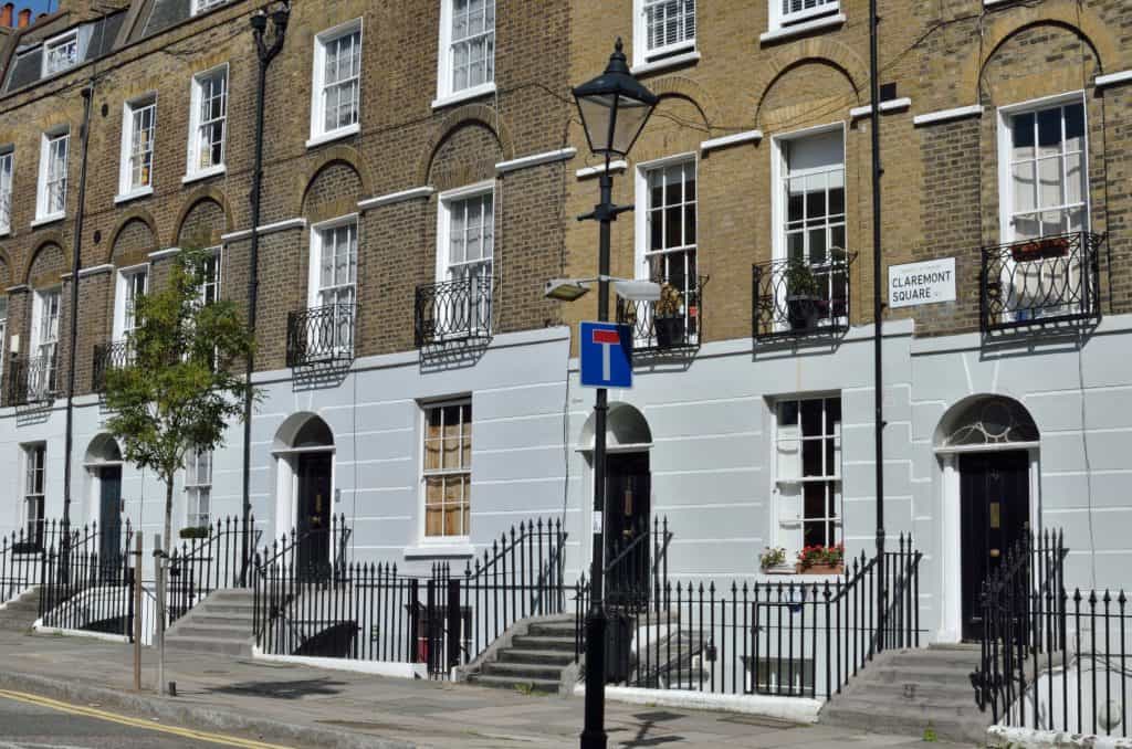 A row of brick townhouses with white facades and decorative railings, reminiscent of Harry Potter locations in London, grace Claremont Square. A dead-end street sign is visible in the foreground, adding an air of mystery to the scene.