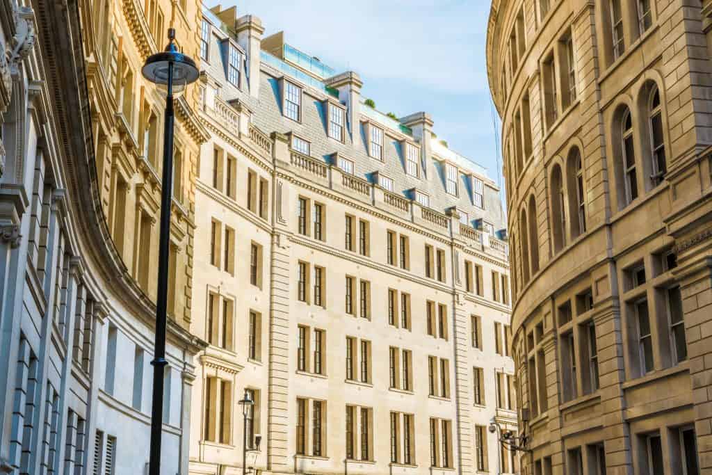 Curved facade of a historic building with large windows and ornate stonework lining a narrow street under a clear sky.