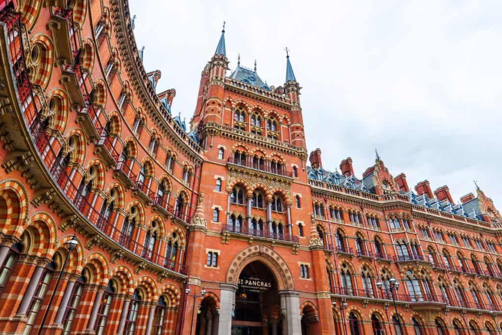 Historic red-brick building in London, with arched windows and ornate towers, known as St. Pancras Renaissance Hotel, on a cloudy day.