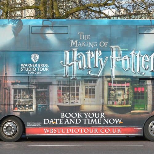 A double-decker bus wrapped in Harry Potter-themed graphics highlights one of the top Harry Potter things to do in London: "The Making of Harry Potter" tour by Warner Bros Studio Tour London.
