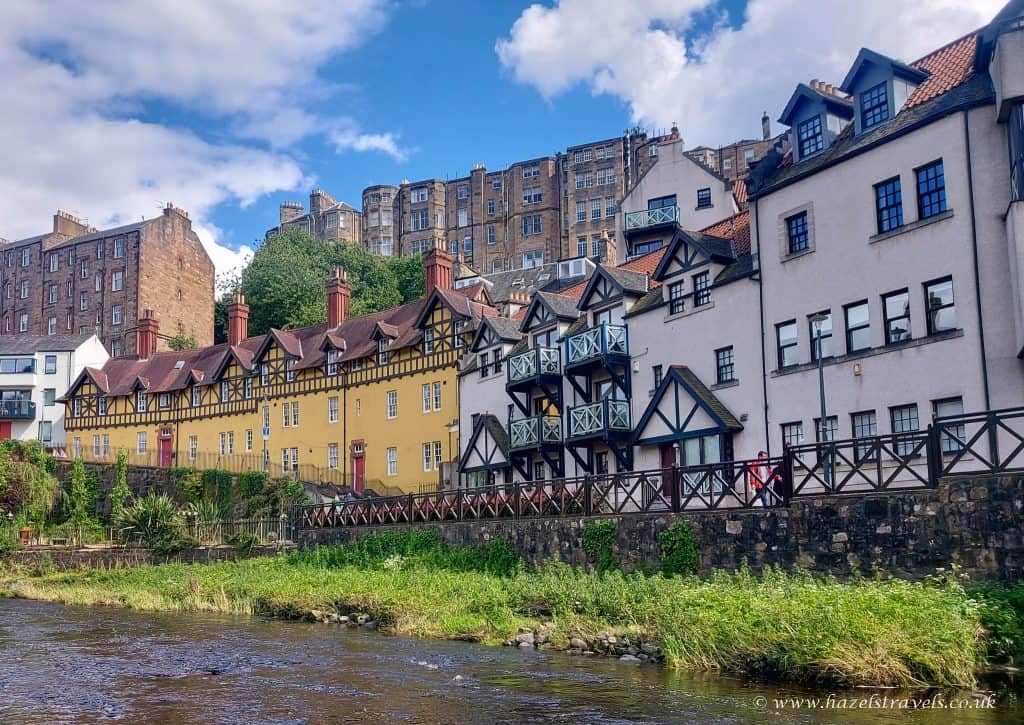 Colorful historic buildings line a river under a partly cloudy sky.