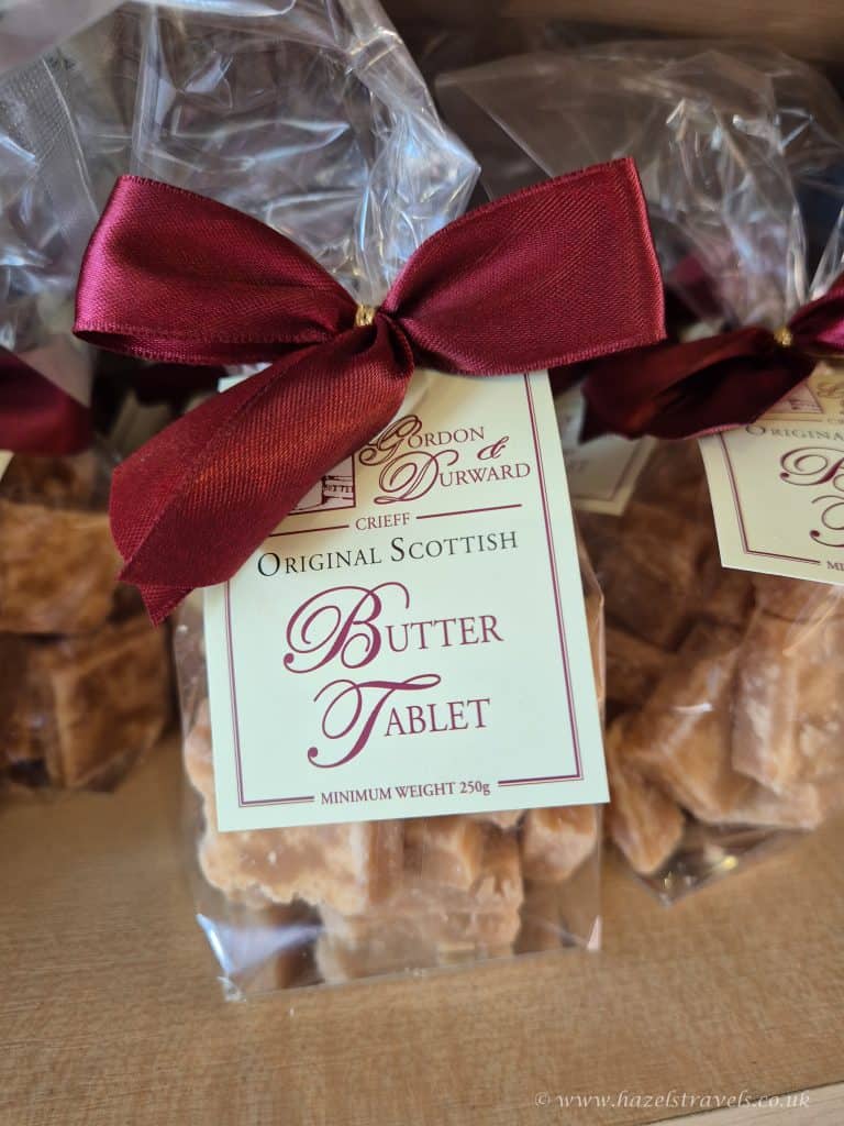 A clear bag of original Scottish butter tablet, tied with a red ribbon and labeled as a 250g product from Gordon & Durward.