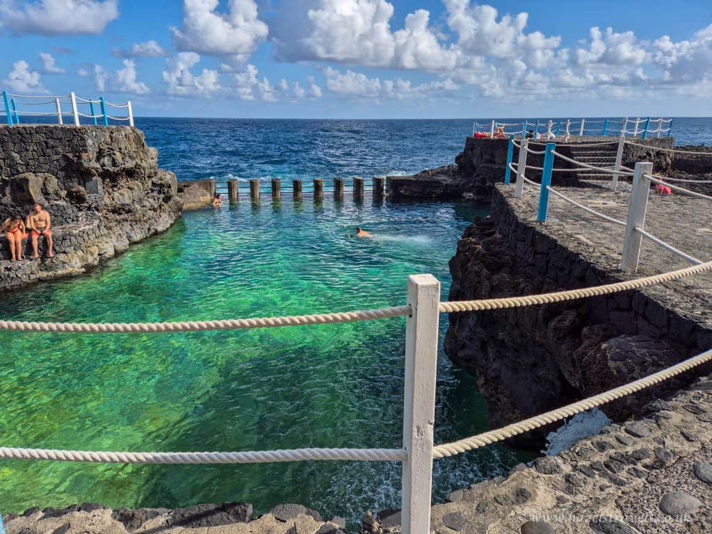Brightly coloured natural rock pool on the coast of Tenerife, Canary Islands, with clear blue water and ocean views. Perfect for relaxing and enjoying a tropical holiday.