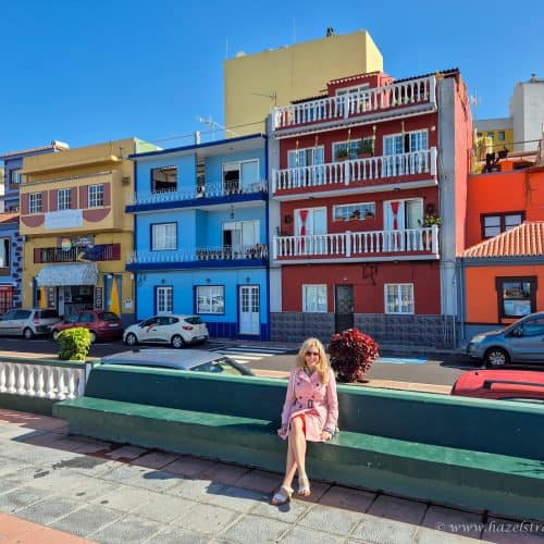 Colourful houses in a seaside town with a woman sitting on a bench, embodying vibrant travel destinations in Canary Islands, ideal for travel photography and exploring local culture.