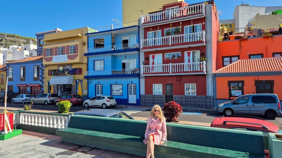 Colourful houses in a seaside town with a woman sitting on a bench, embodying vibrant travel destinations in Canary Islands, ideal for travel photography and exploring local culture.