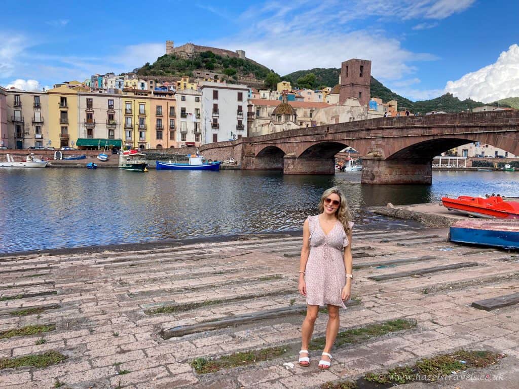 Picturesque woman sightseeing in the colourful coastal town of Cefalù, Sicily, with historic buildings, boats, and a medieval castle on a hill in the background, perfect for travel enthusiasts.
