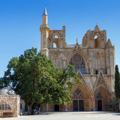 Majestic Gothic cathedral with intricate stone carvings and towering spires, set against a clear blue sky in a historic European town.