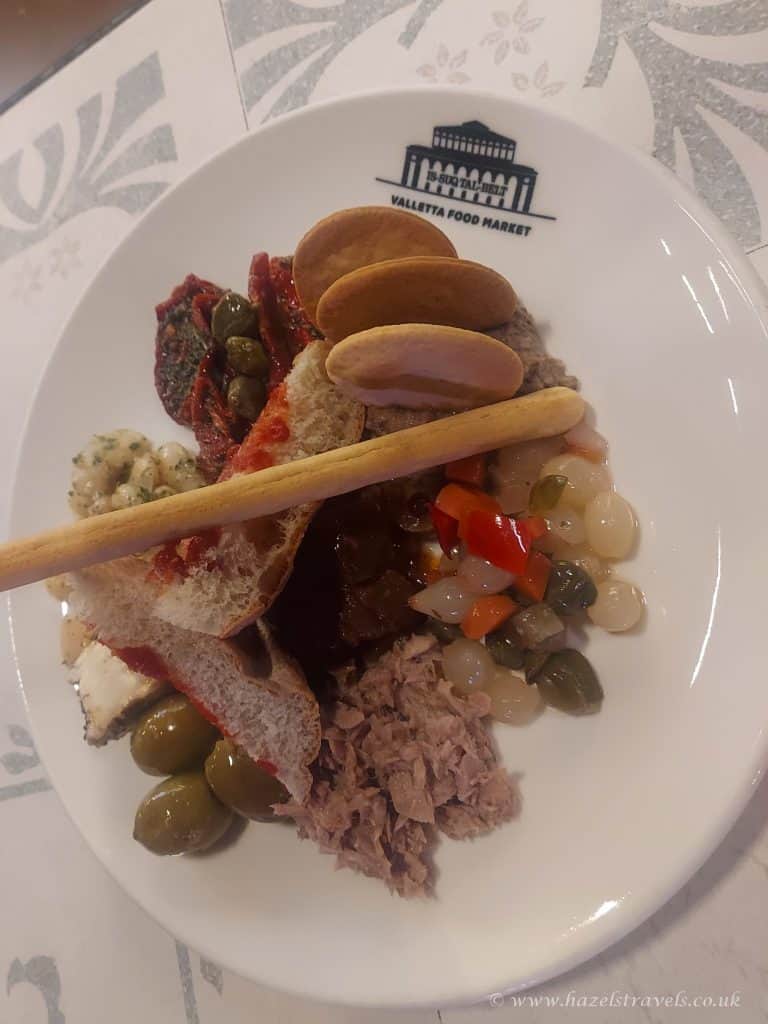 Mediterranean antipasto platter with olives, bread, pâté, and cured meats on a Valetta Food Market plate.