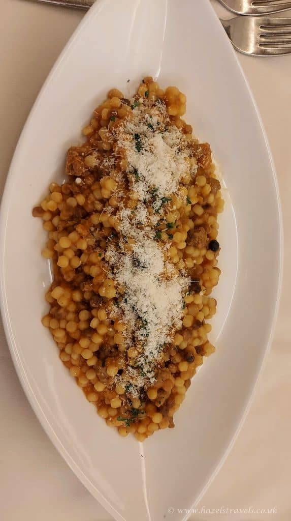 Chickpea and vegetable stew served on a white oval plate, garnished with grated cheese and herbs, typical of comforting and healthy meal options.