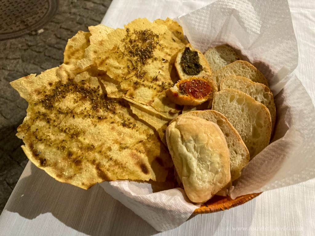Crispy Italian bread and garlic bread slices served in a basket with napkin, showcasing delicious traditional Italian side dishes. Perfect for sharing at Italian restaurants or home.