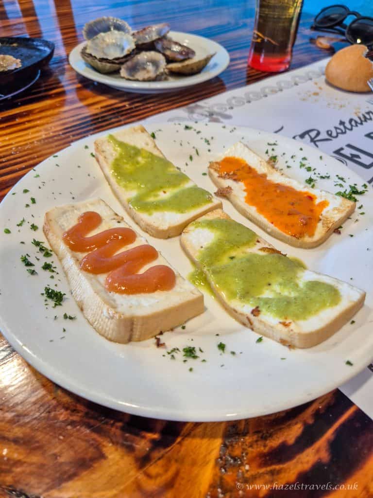 Canaria goats cheese with various toppings including ketchup, green and orange sauces, served on a white plate at a seaside restaurant.