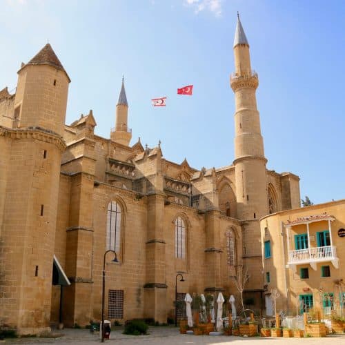 Stunning view of a historic Middle Eastern castle with tall minarets, beige stone walls, and blue sky, showcasing architecture and cultural landmarks.