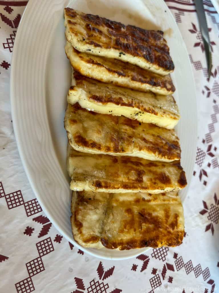 Golden-brown fried cheese on a white oval plate, served in a cozy setting, representing delicious traditional British pub food.