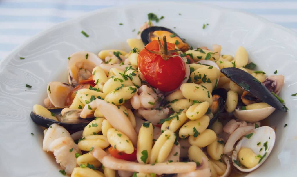 Fresh seafood pasta with cherry tomato, herbs, and mixed shellfish - vibrant Italian cuisine from Hazel's Travels.