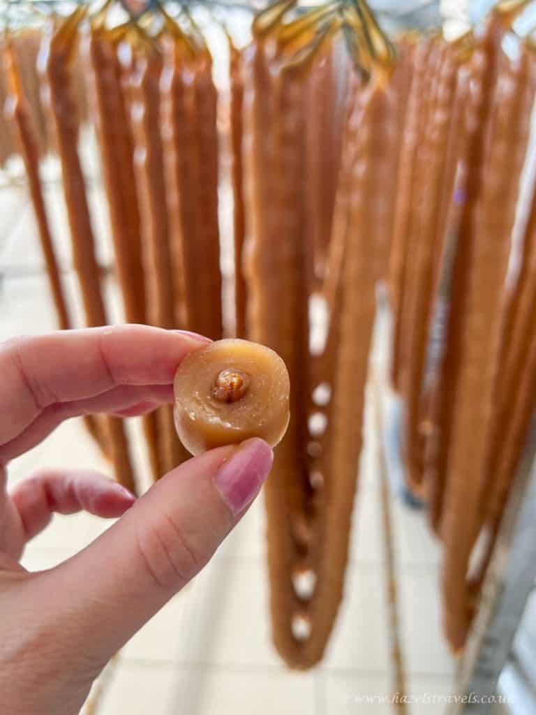 Smoked caramel candy being held in front of a display of caramel swizzle sticks.
