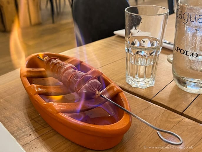 Yum risotto served in a rustic setting with a flaming skewer, clear glass of water, and stylish glass bottle, perfect for enjoying authentic Italian cuisine during travel adventures.