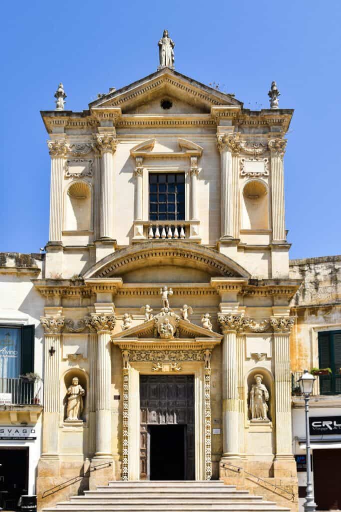 Elegant historic church facade with classical architecture and intricate sculptures, captured in bright sunlight.